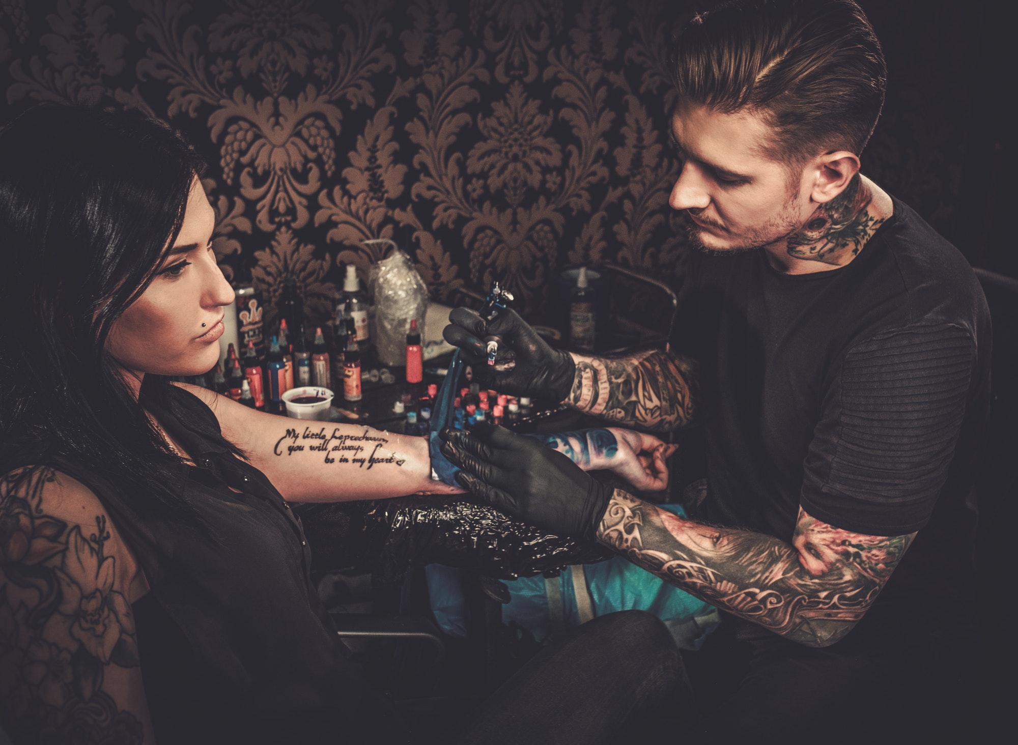 Professional tattoo artist makes a tattoo on a young girl's hand.